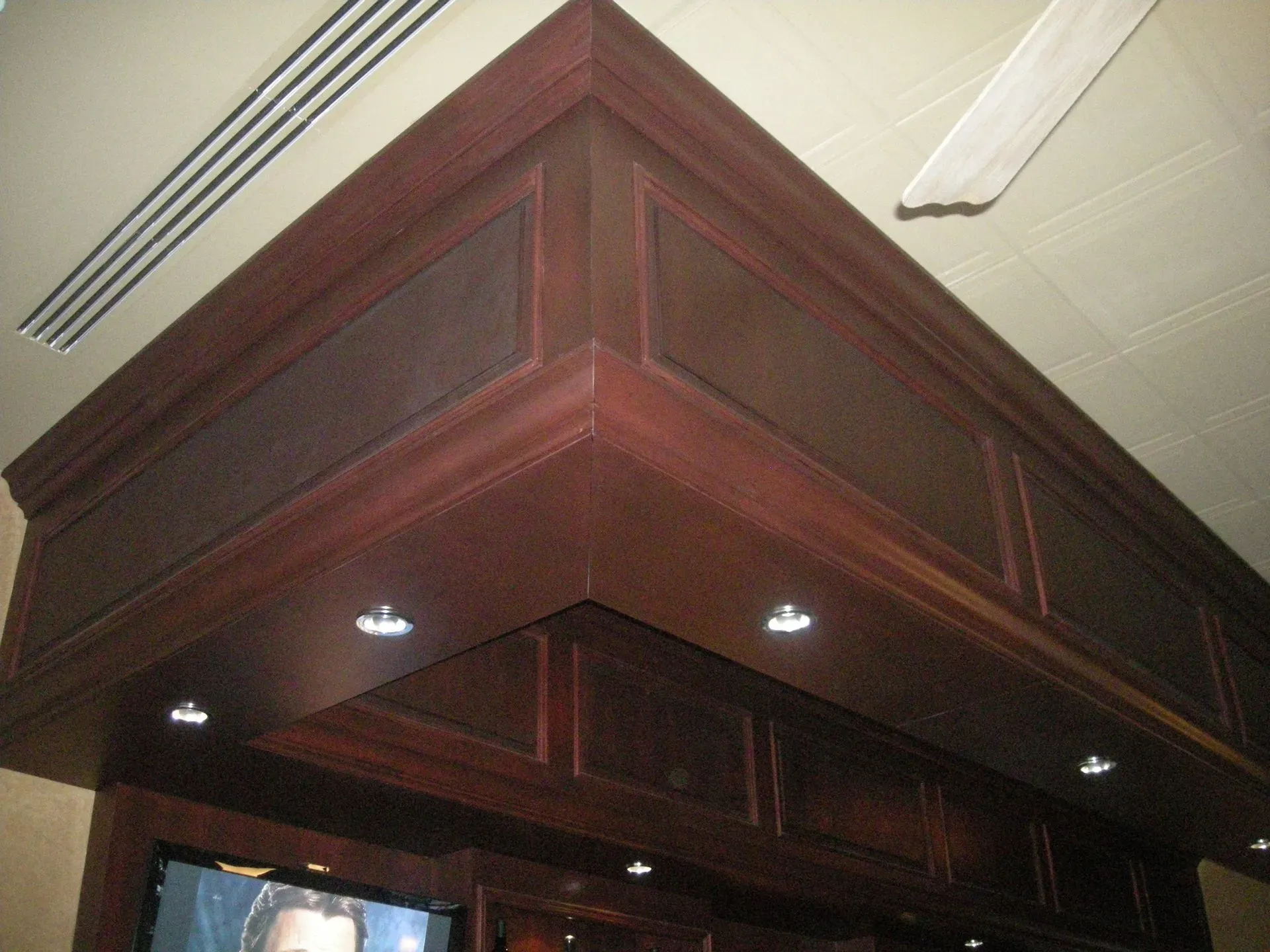 Dark wooden ceiling canopy with recessed lights in an indoor room
