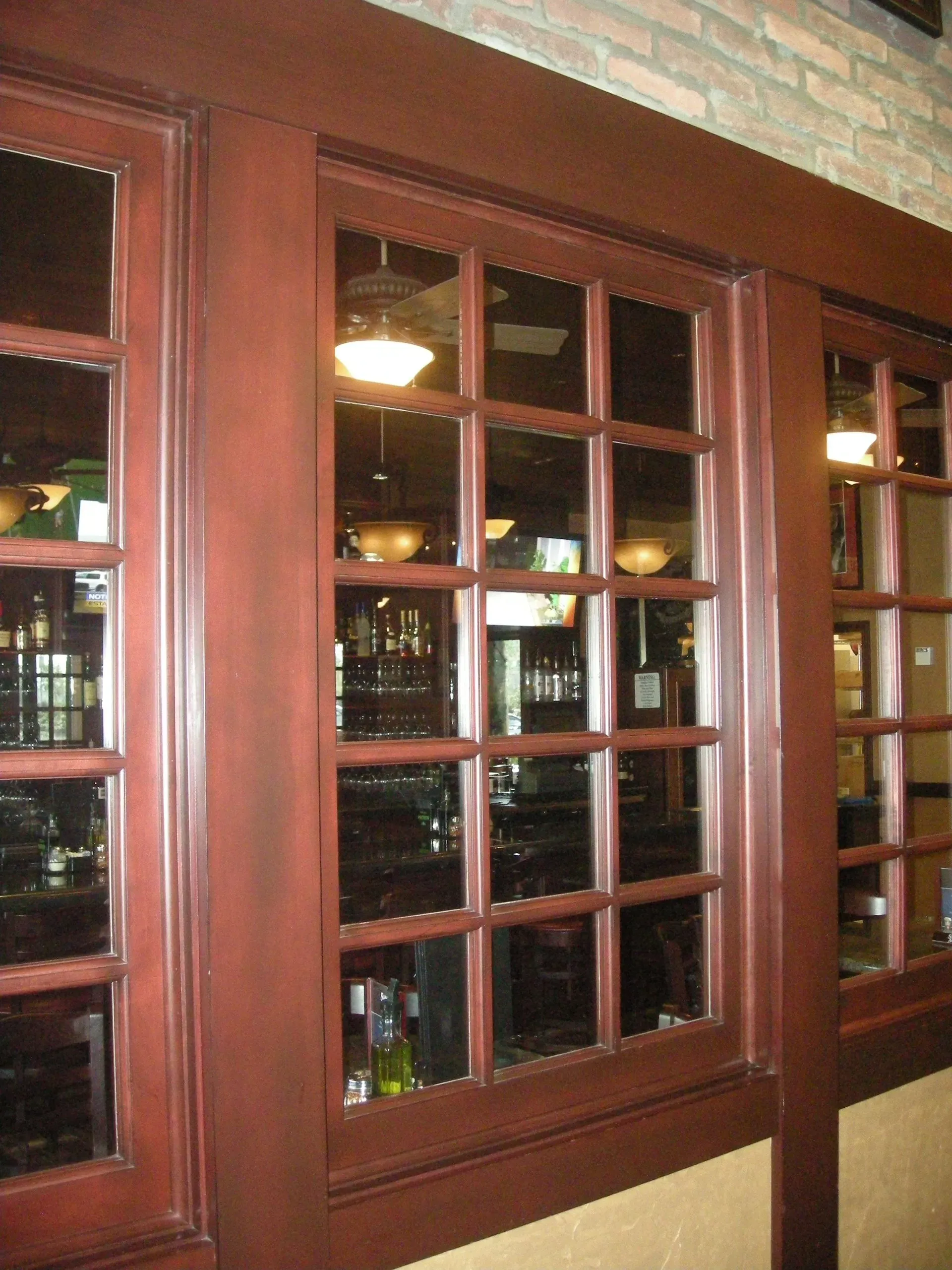 Wooden-framed glass windows reveal shelves of bottles inside a warmly lit room.