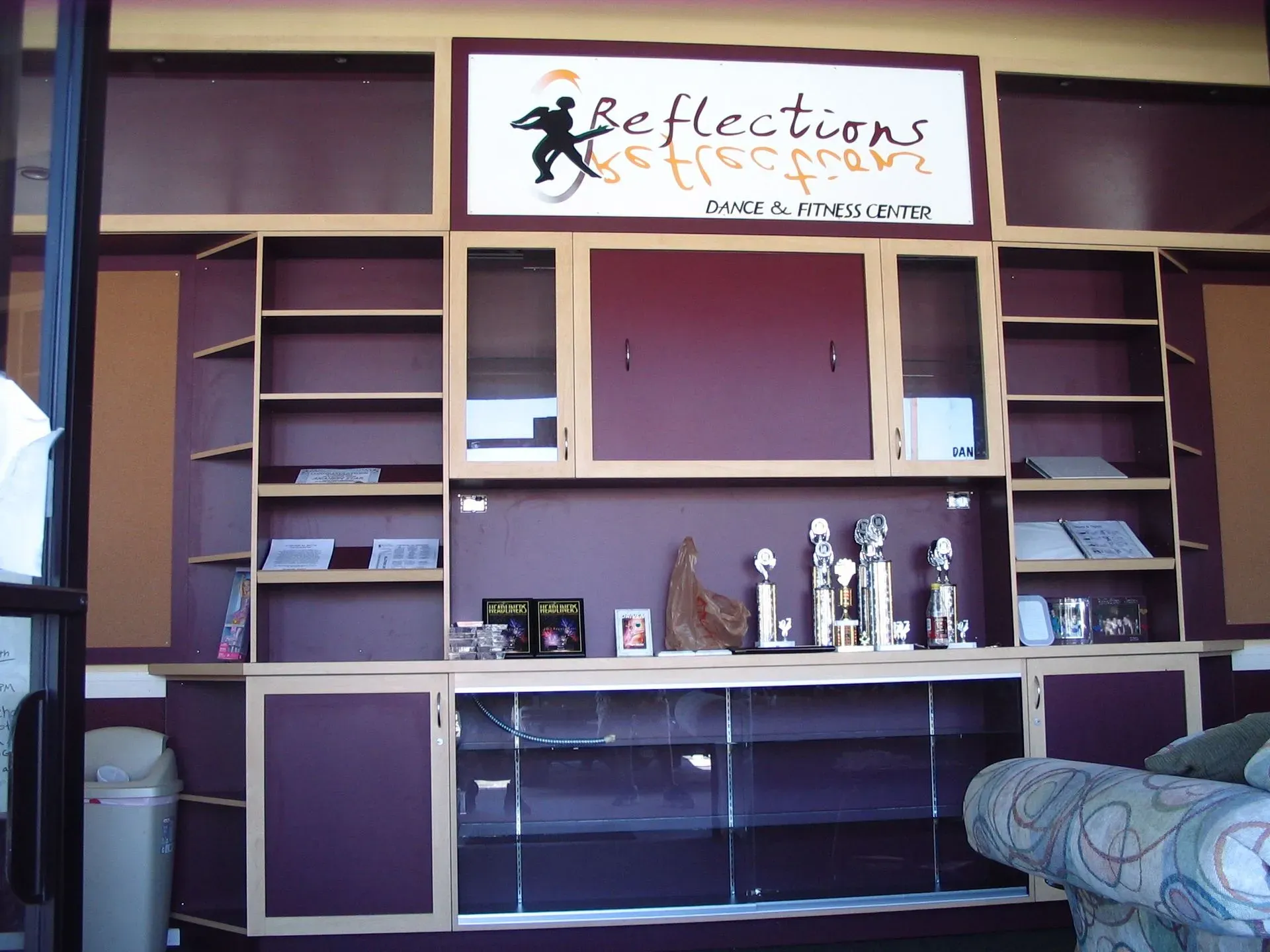 Purple salon shelving and display wall with a “Reflections” sign, mirrors, and decorative items