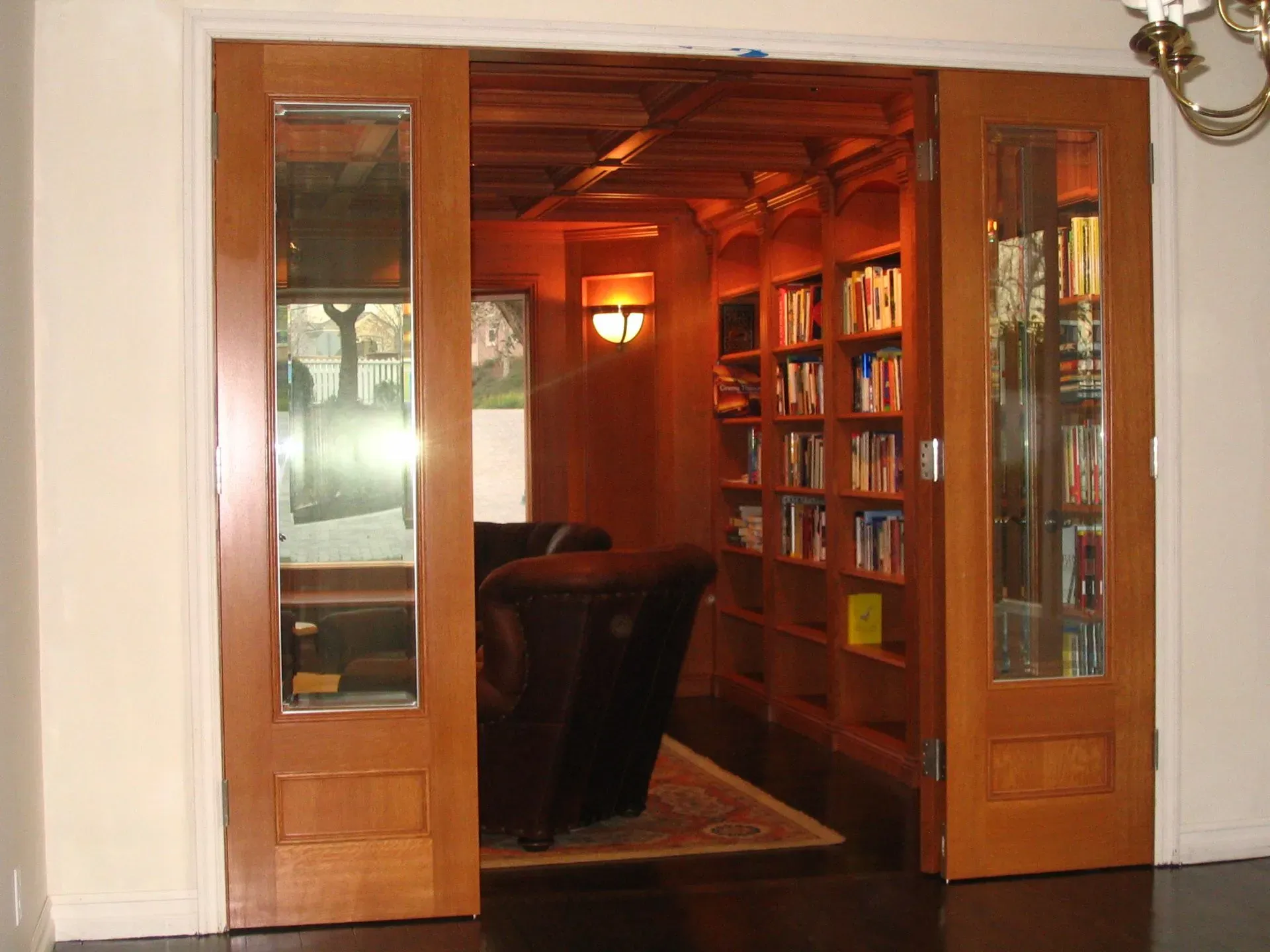 Wood-paneled library entrance with open double doors, bookshelves, and a leather chair inside