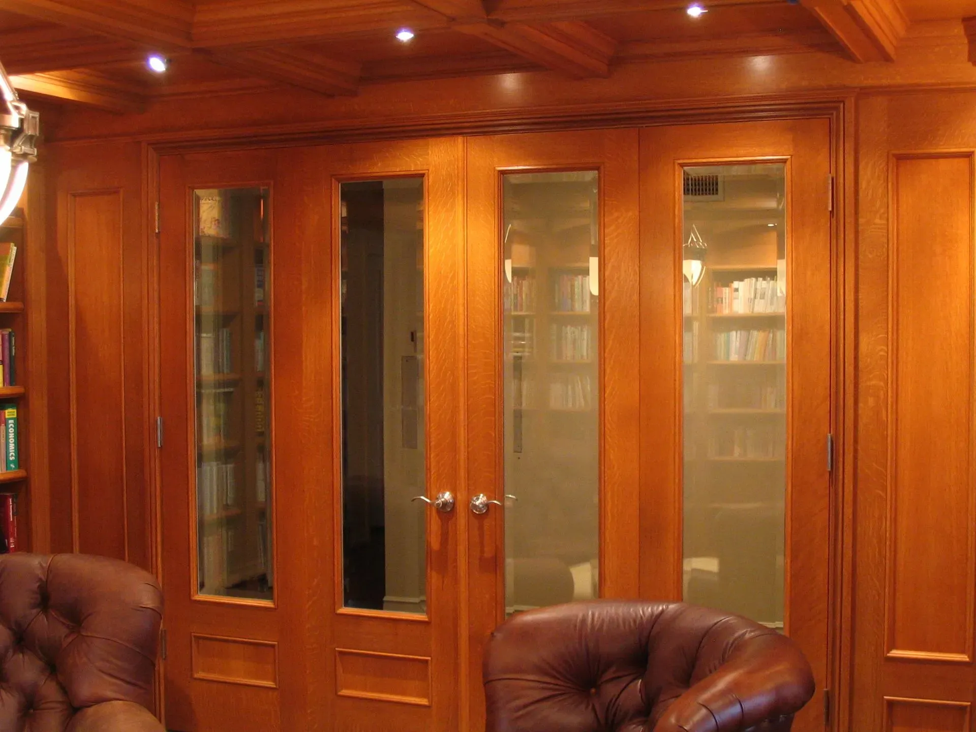 Wood-paneled room with glass-front cabinets, warm ceiling lights, and leather chairs