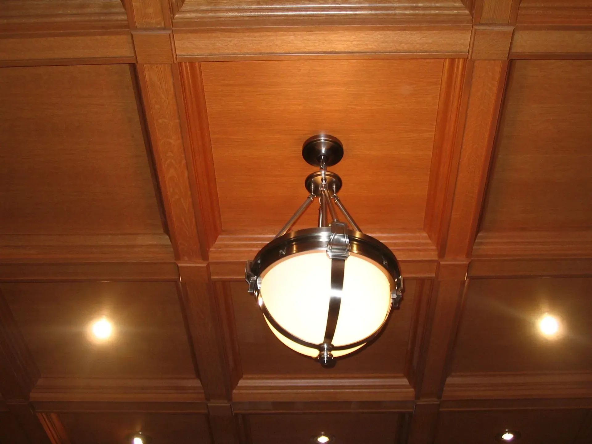 Wood-paneled ceiling with a central hanging light fixture and recessed spotlights on either side.