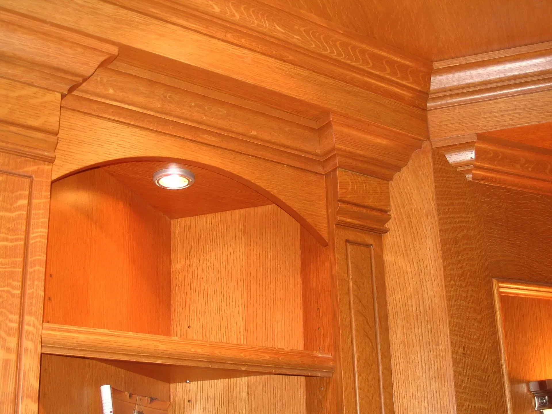 Wooden kitchen cabinets with arched shelves and warm recessed lighting