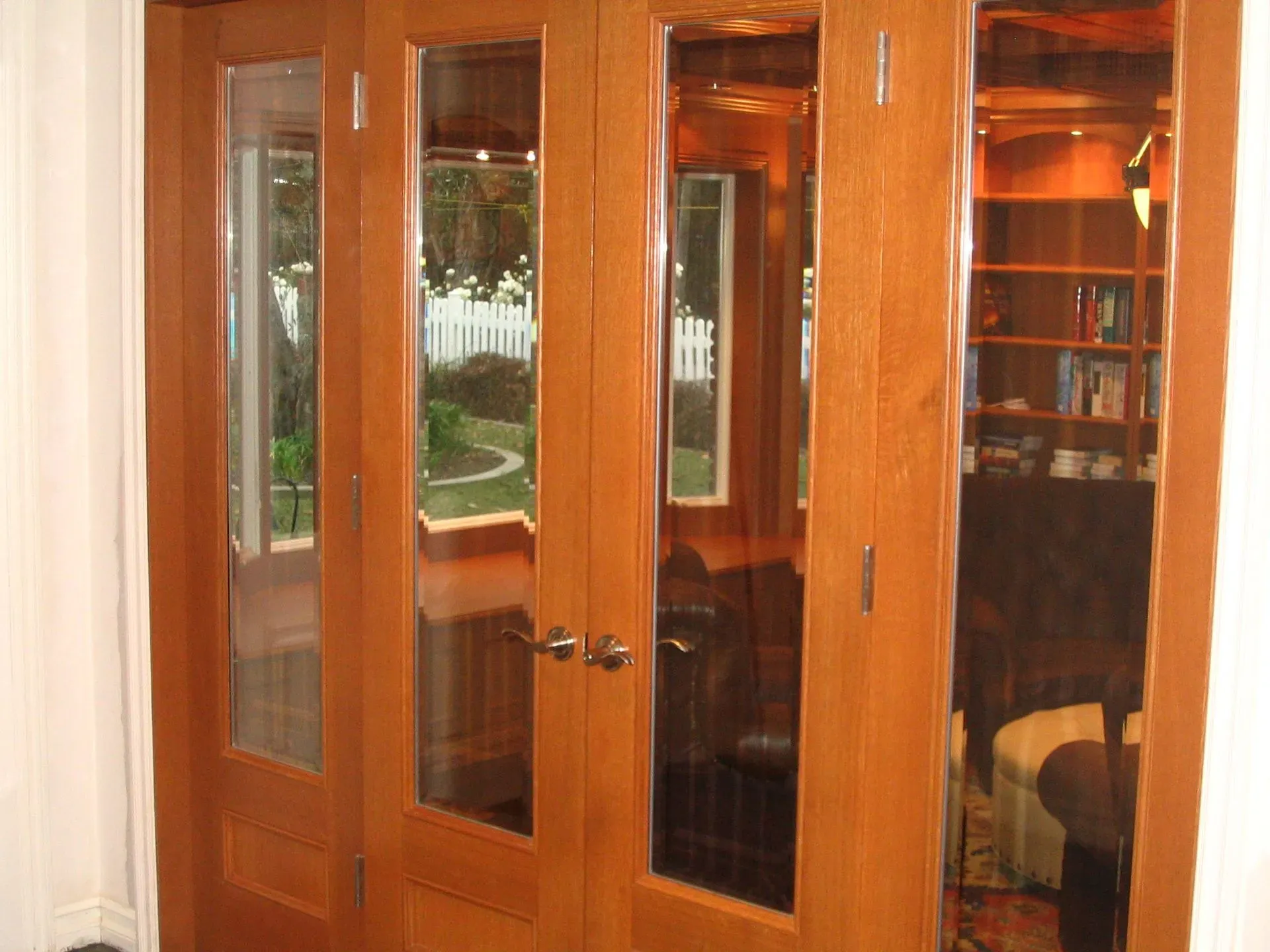 Wooden French doors with glass panes opening into a warmly lit home office or study