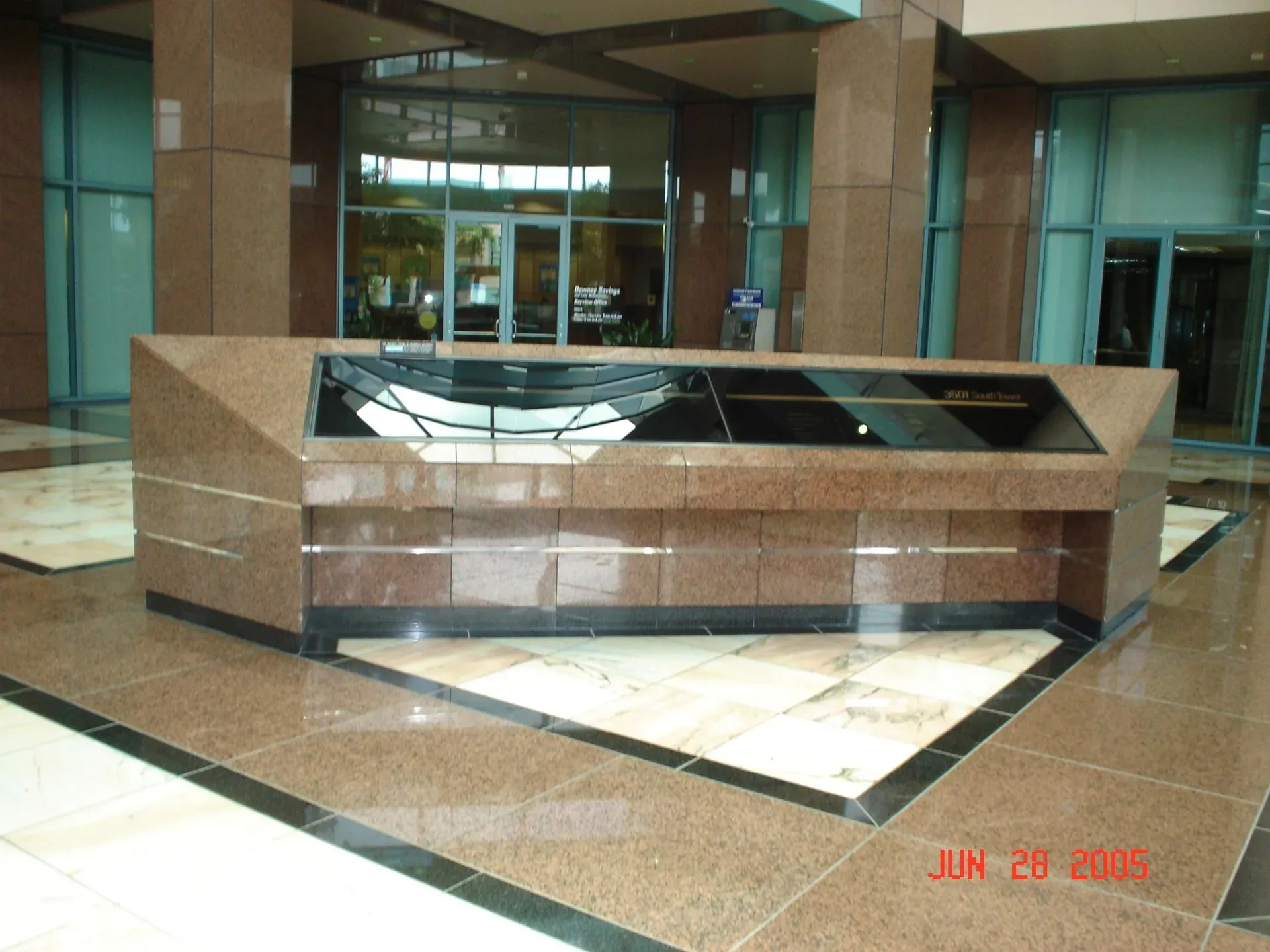 Marble information kiosk in a building lobby with glass walls and polished floors