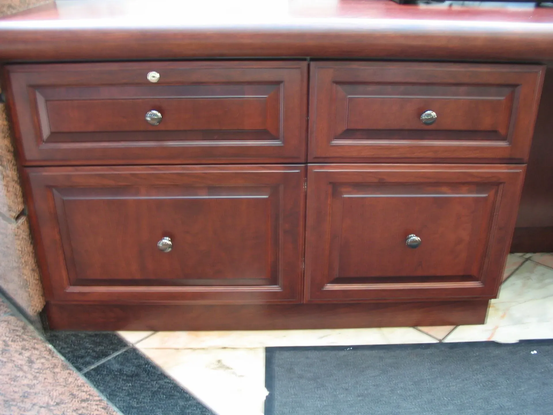 Wooden bathroom vanity with four cabinet doors and two upper drawers on a tiled floor