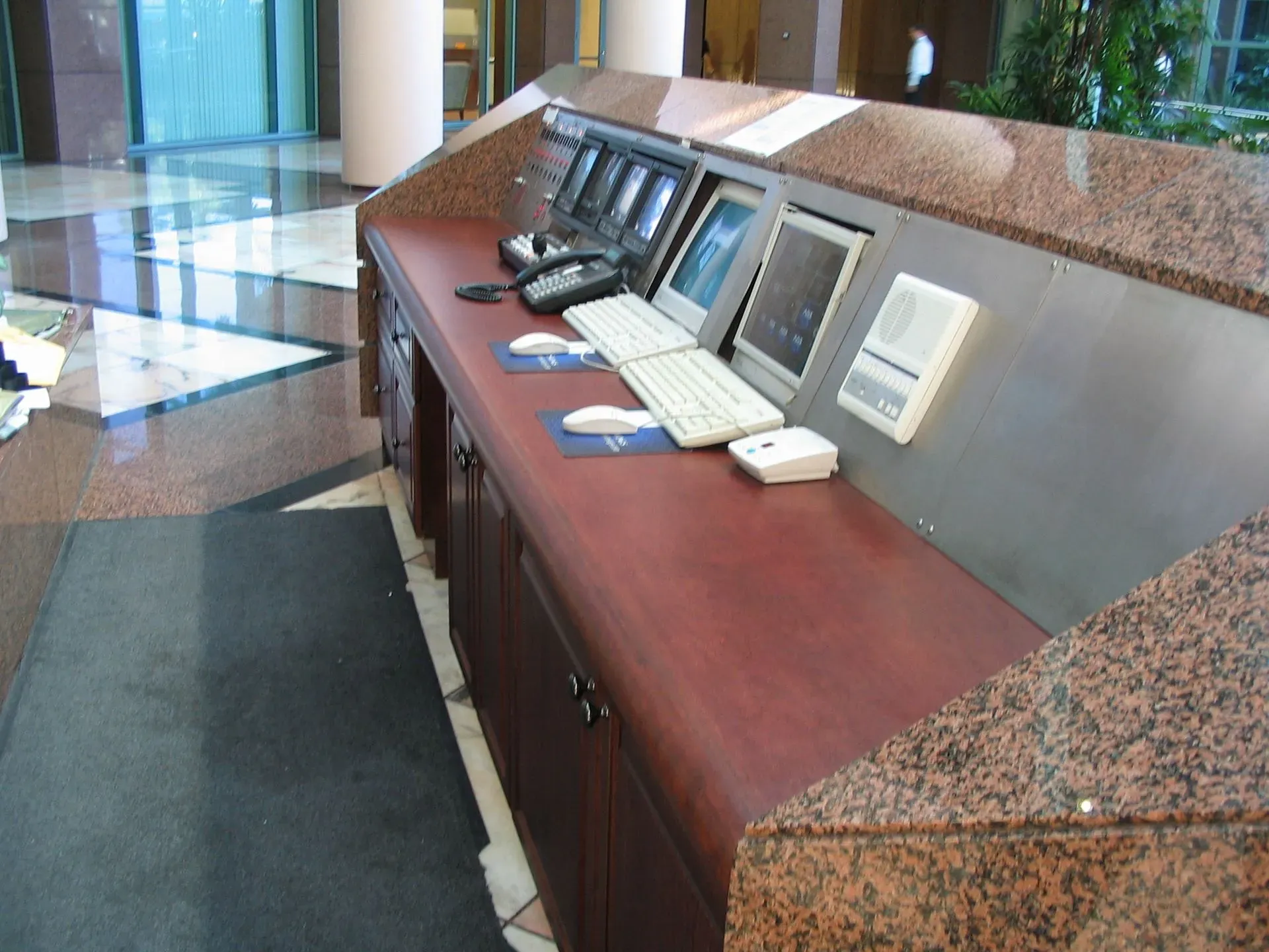 Lobby counter with computers and a keyboard in a marble and wood reception area.