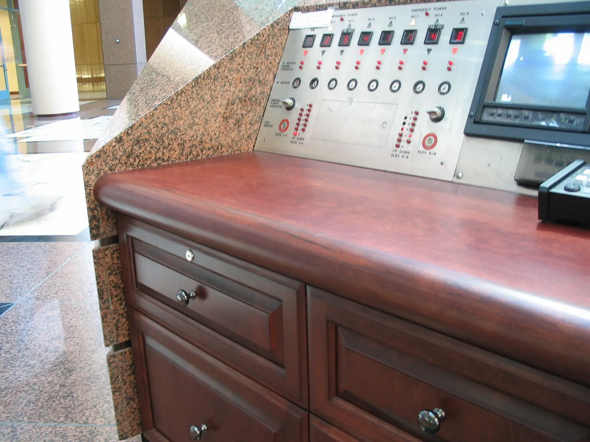 Wooden countertop with drawers beside a control panel and monitor in a bright indoor facility