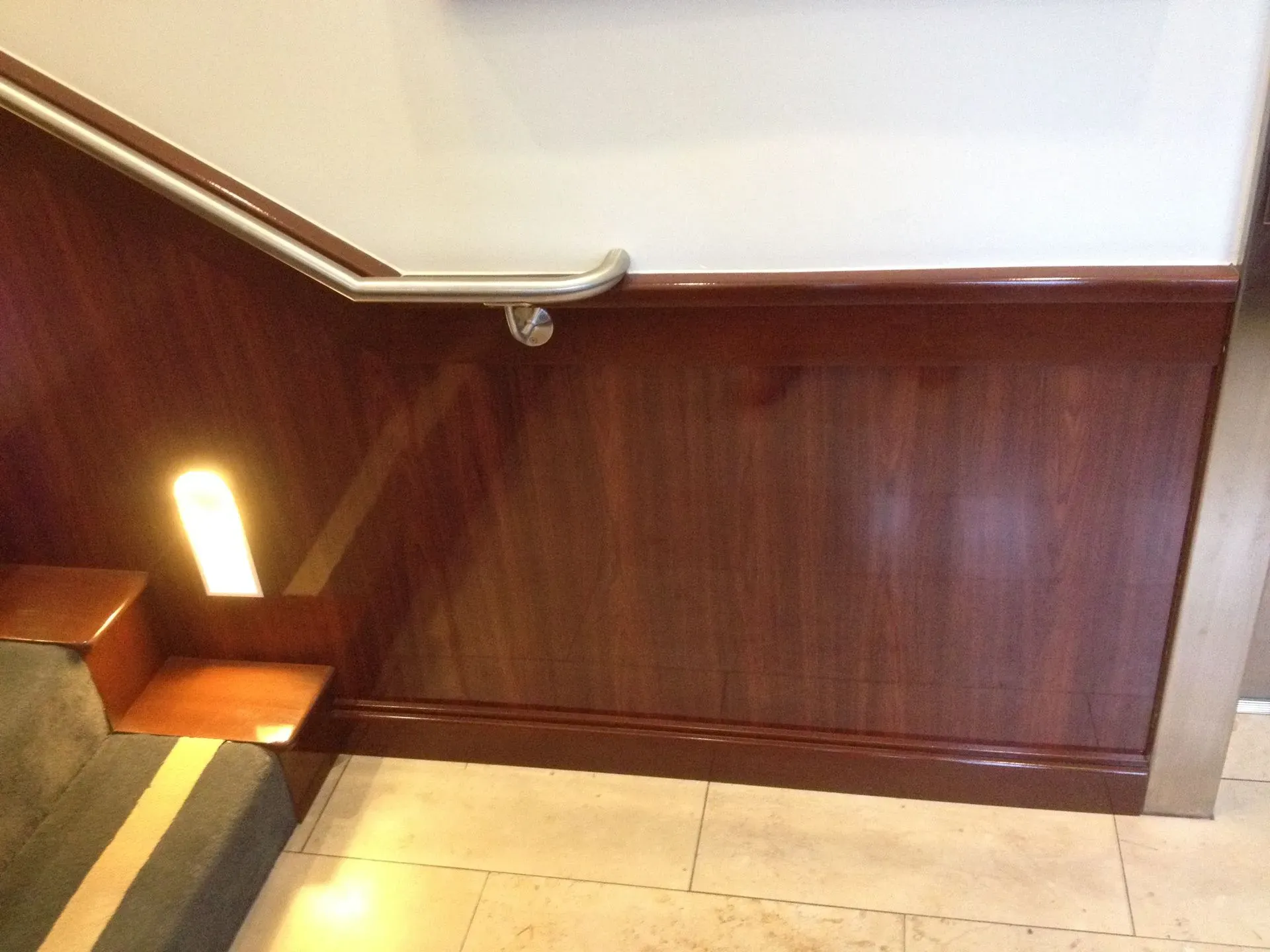 Wood-paneled stairwell with carpeted steps and a bright wall light at the landing