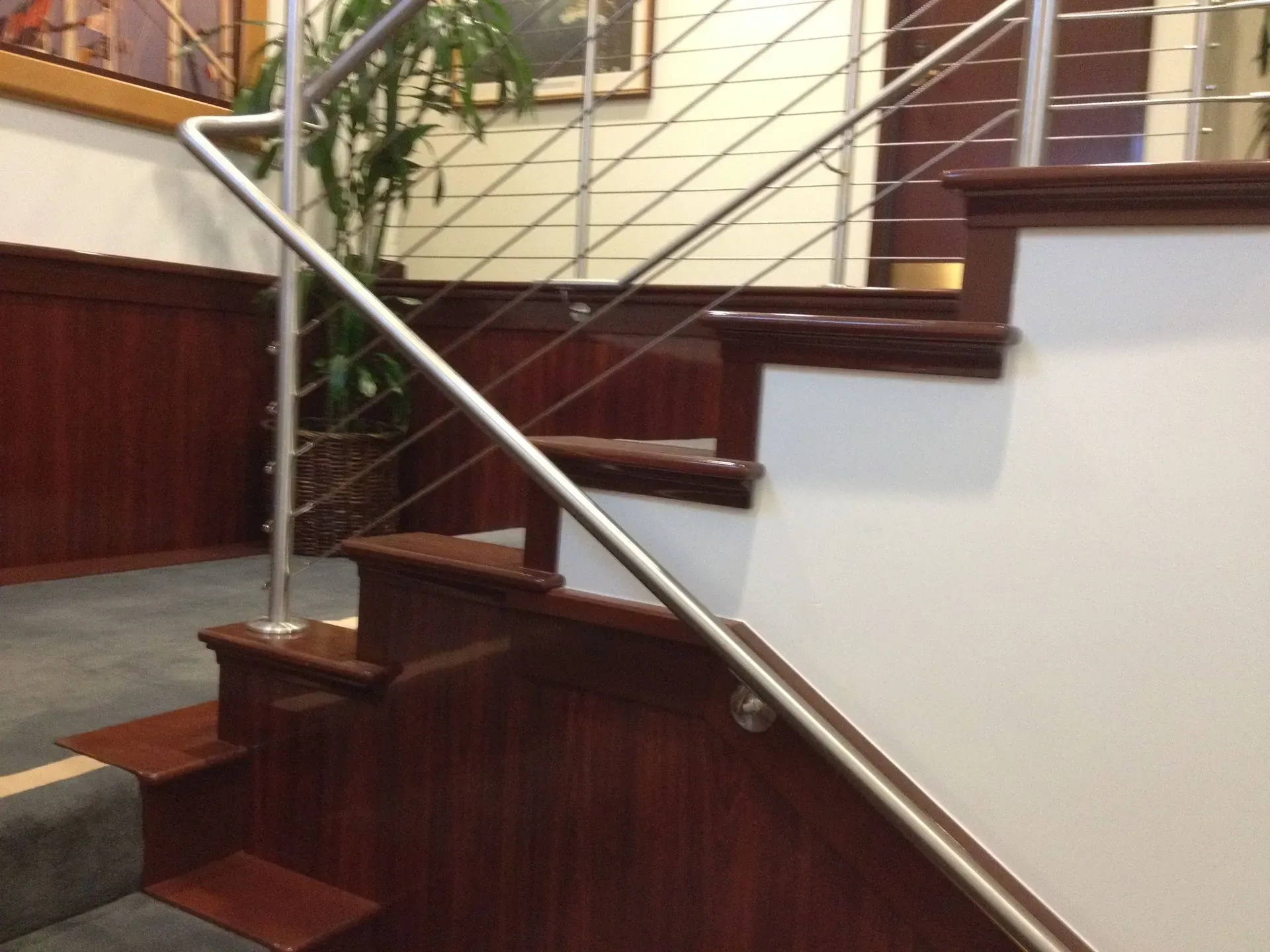 Indoor staircase with dark wood steps and a silver handrail by a white wall