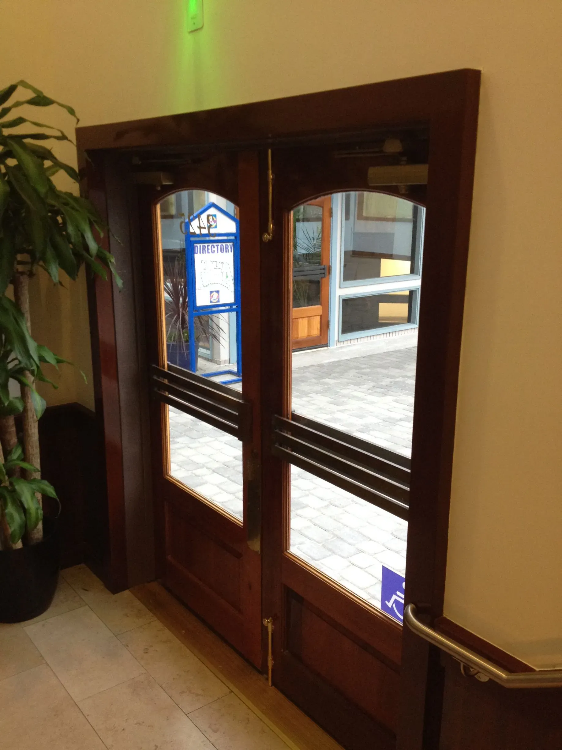 Wood-framed glass double doors in a hallway, leading to an outdoor courtyard.