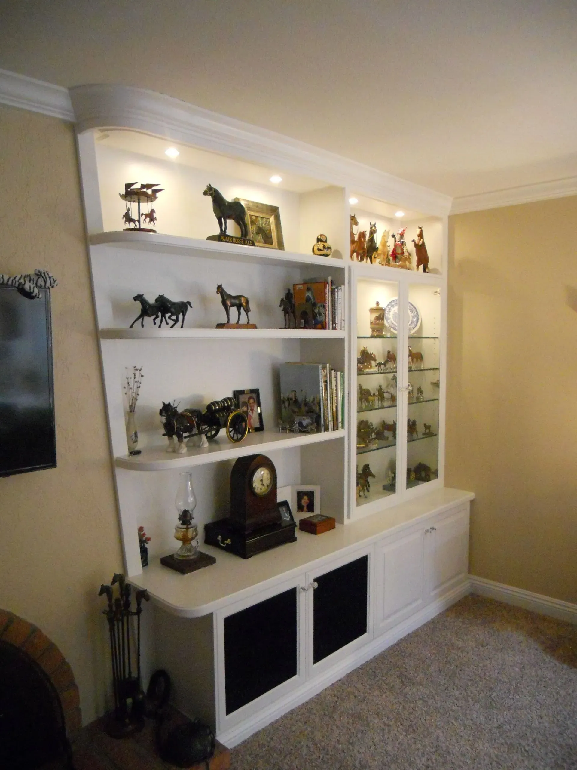 Built-in white shelving unit with black and gold decorative figurines in a beige living room.