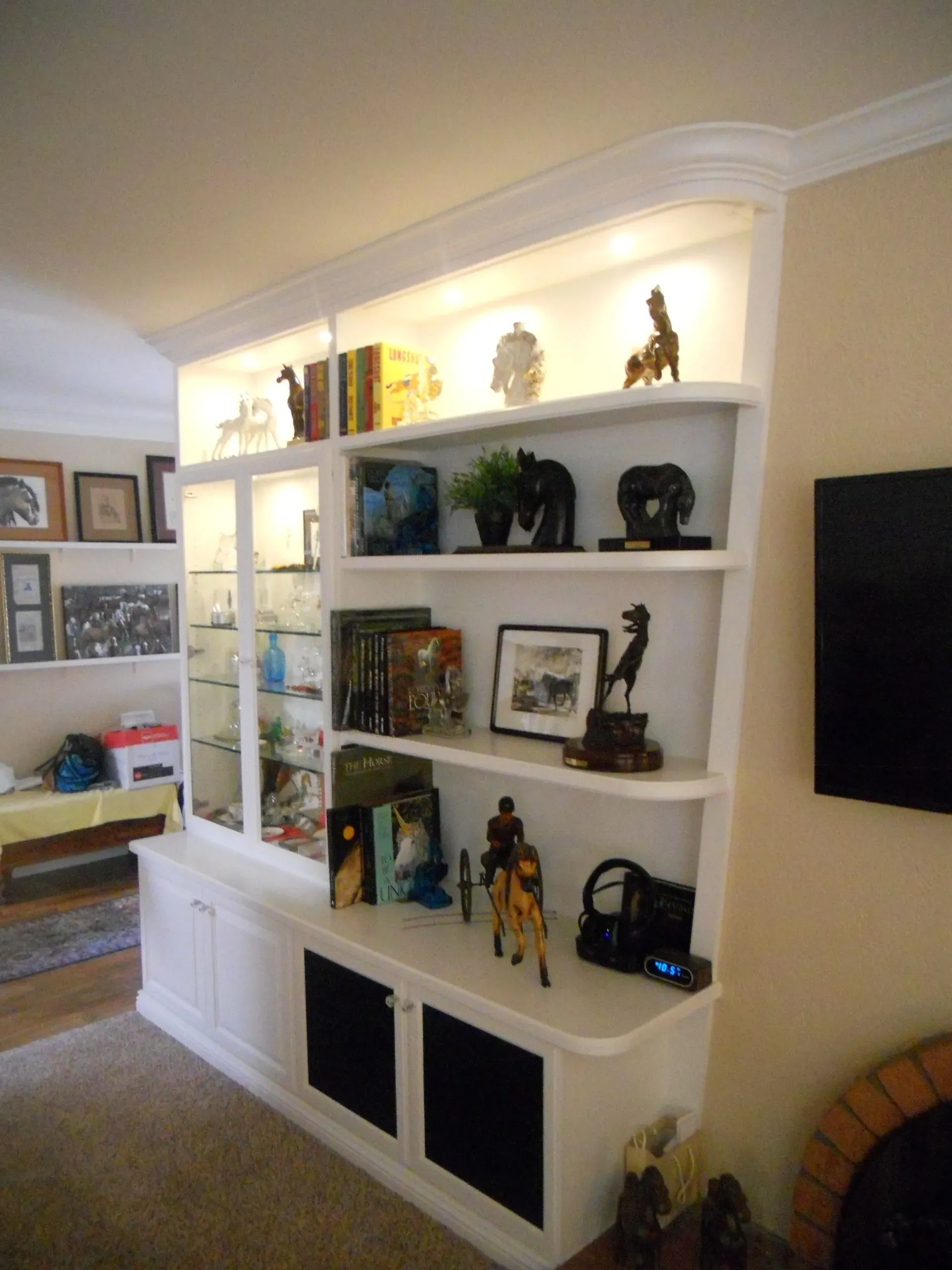 Built-in white shelving with books, plants, and decor in a beige living room