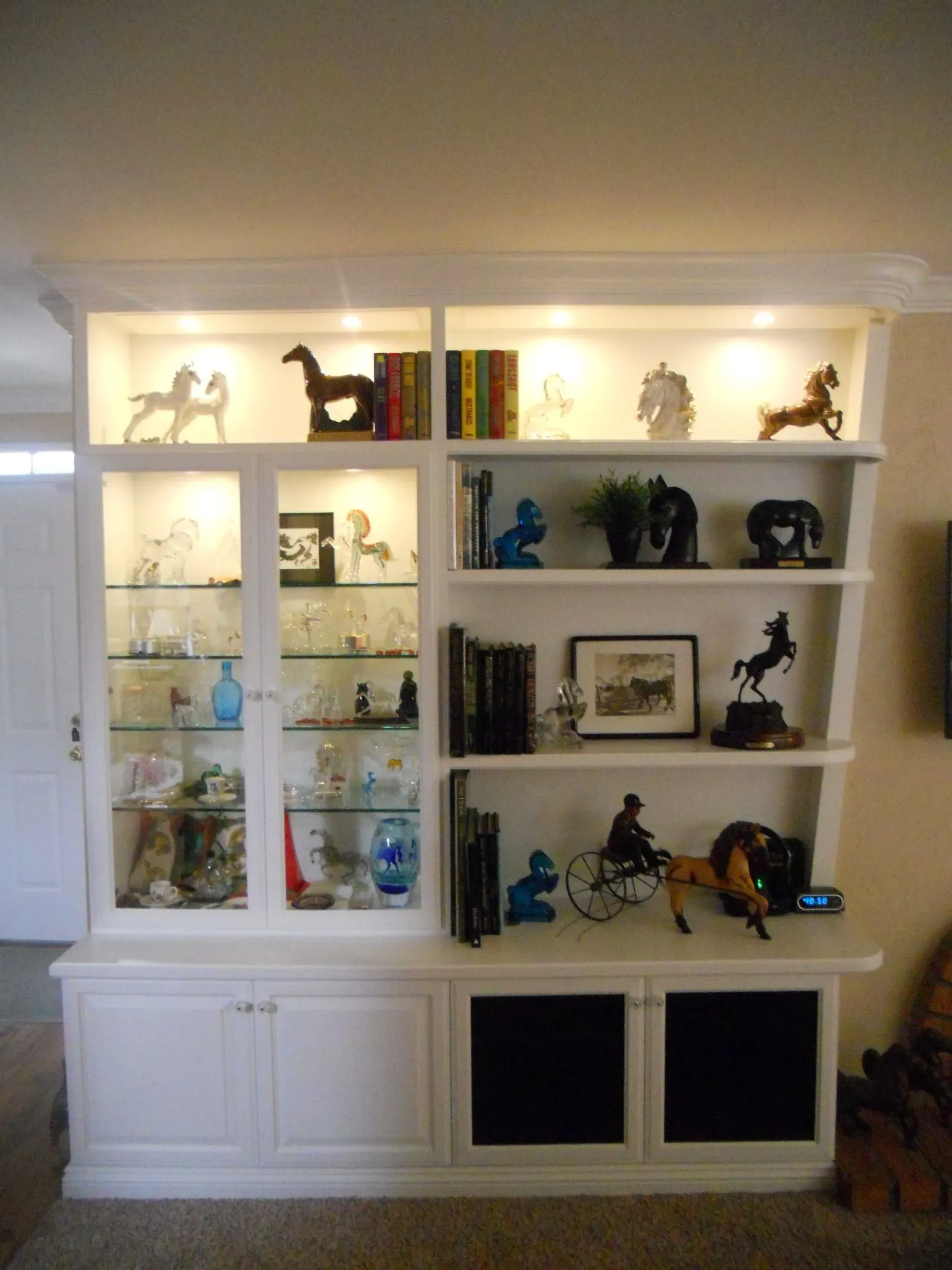 Built-in white bookshelf displaying books, framed art, and decorative figurines in a living room.