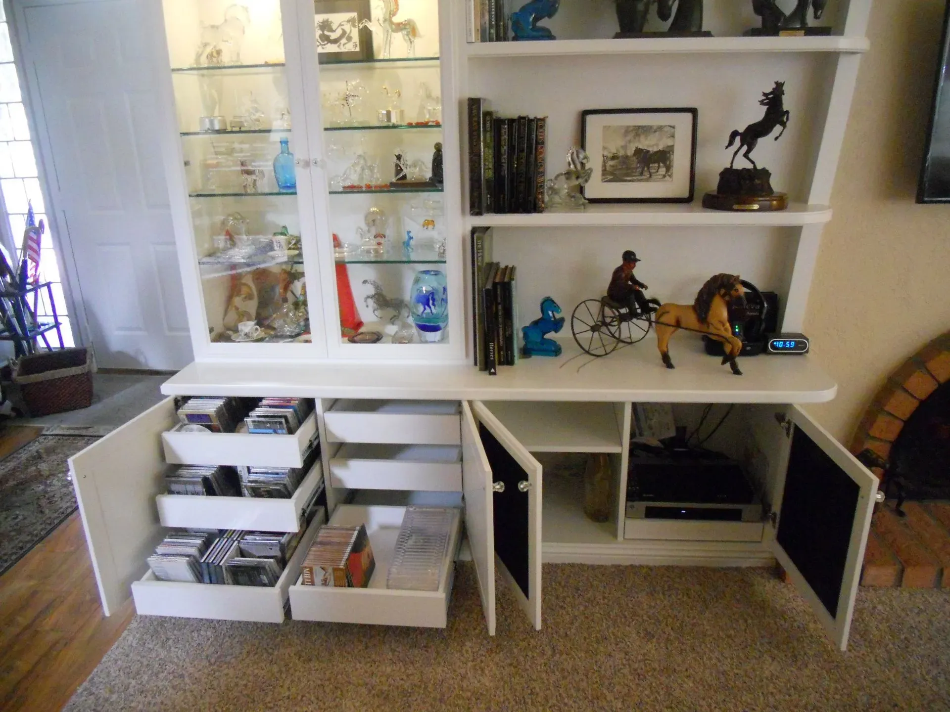 White shelving unit with glass display cabinets, open storage bins, and framed art in a living room