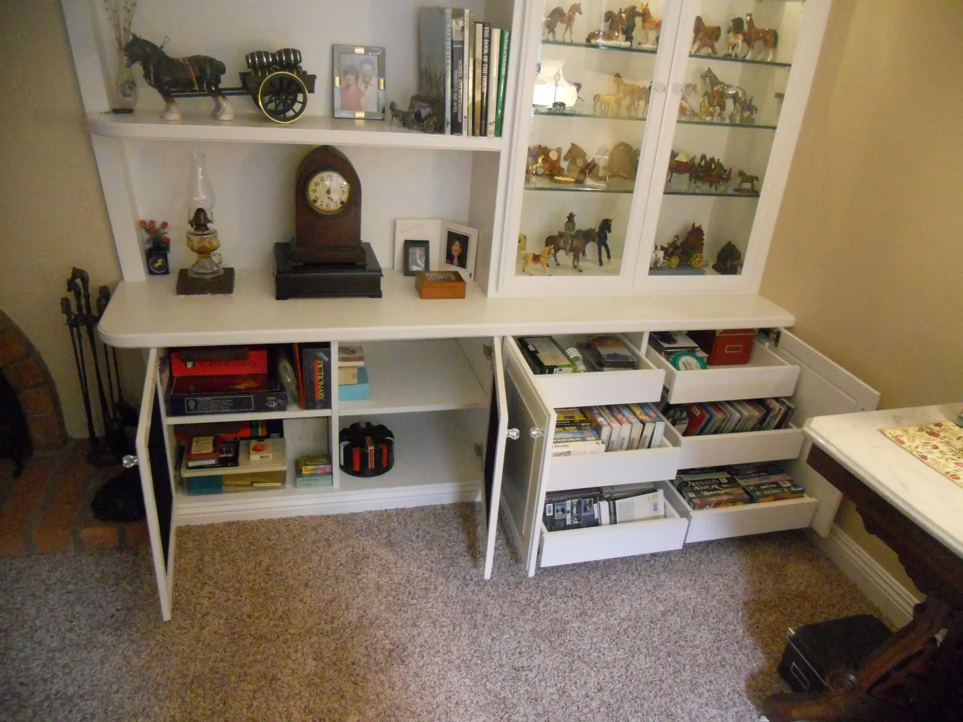 White shelving unit with books, decor, and small storage bins in a carpeted room