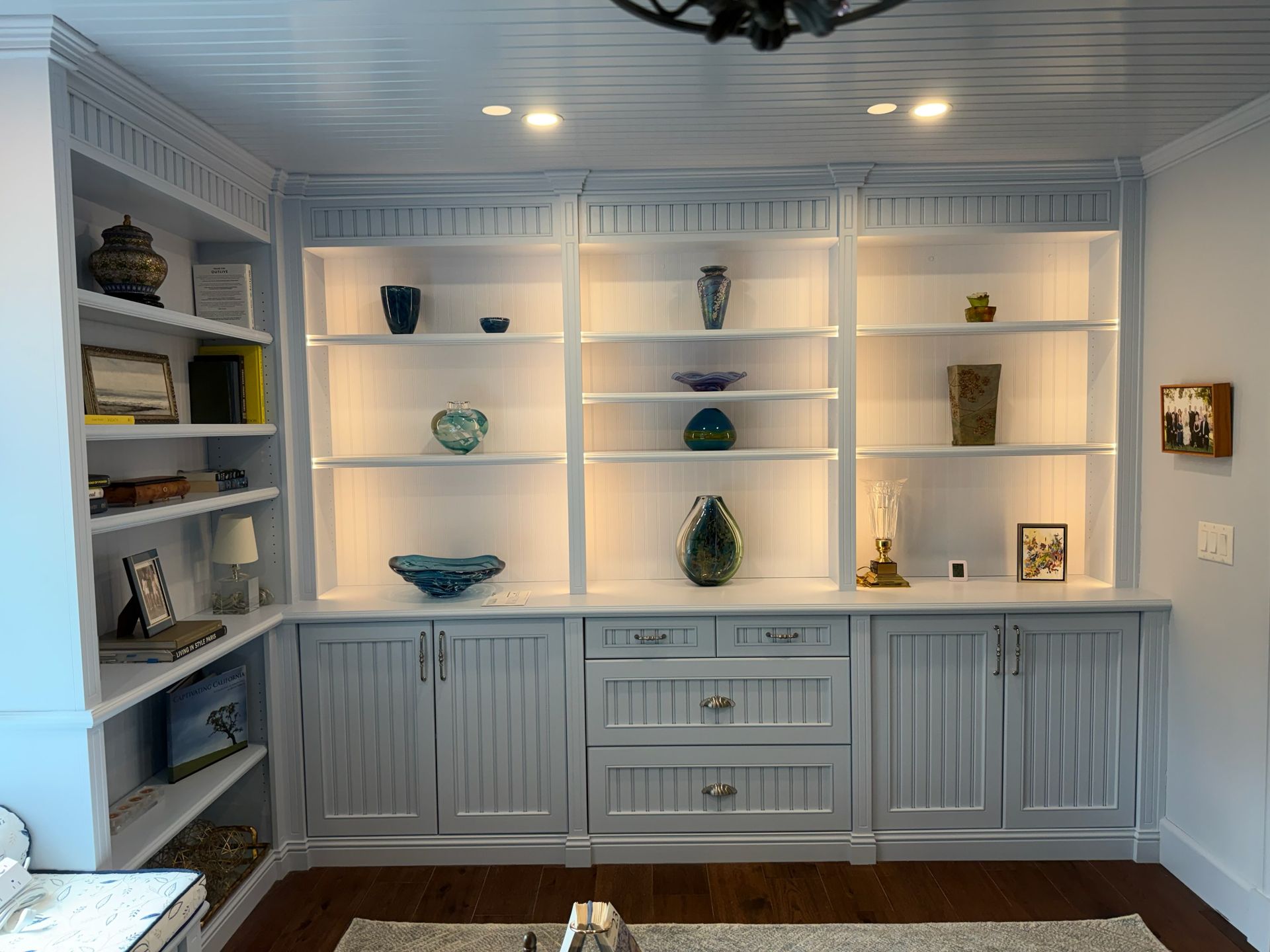 Built-in white display shelves with blue-accent decor and cabinets in a bright room