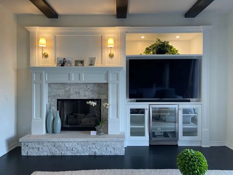 Bright living room with a fireplace, TV, built-in shelves, and a potted plant on a dark floor.