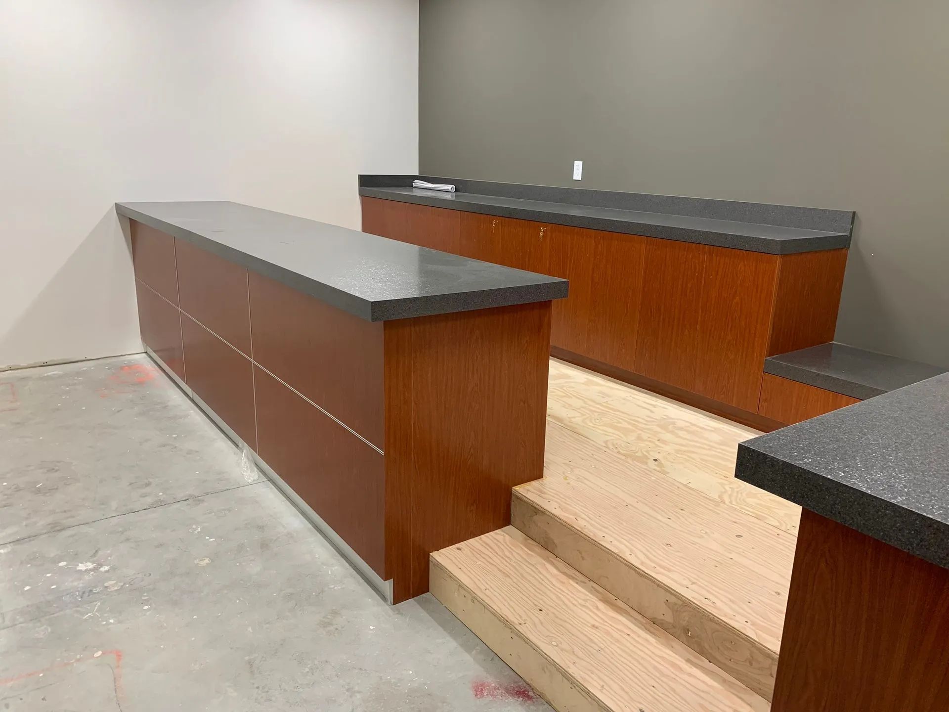 Modern courtroom with wooden benches, dark countertops, and central steps in a minimalist room