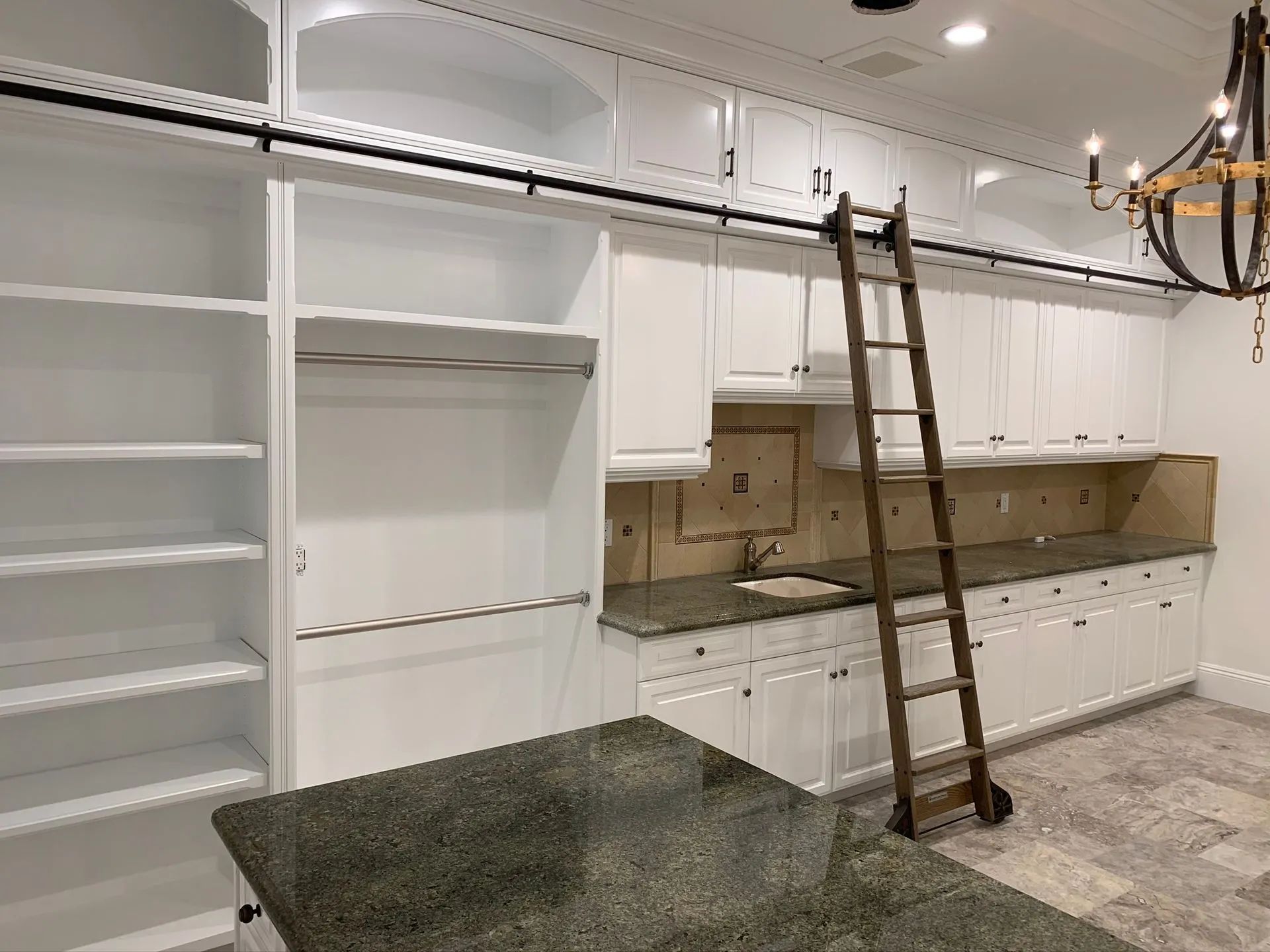Empty kitchen with white cabinets, open shelves, and a ladder leaning against the wall.