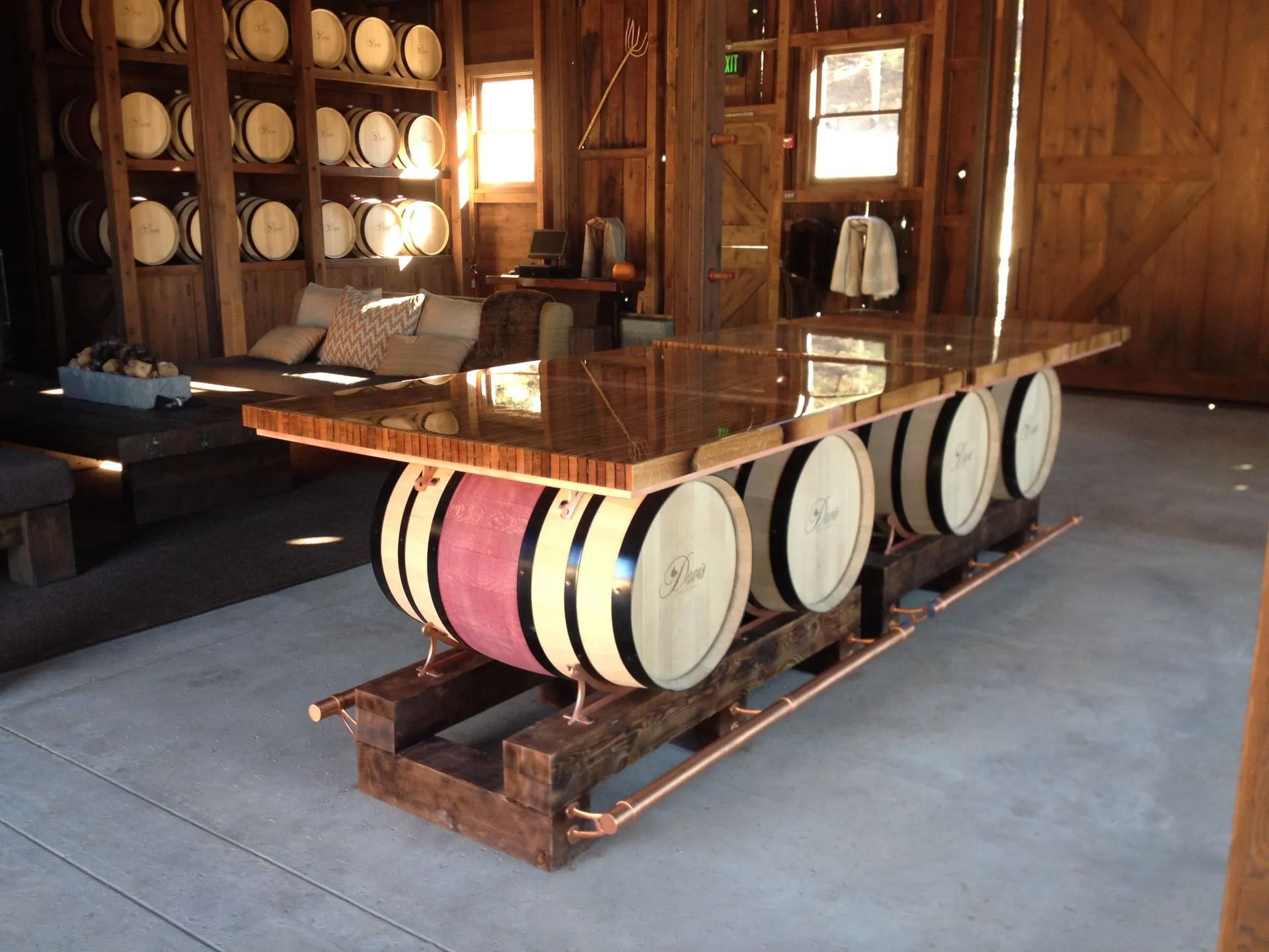 Wine barrel dining table in a rustic wooden room with barrels stacked along the walls