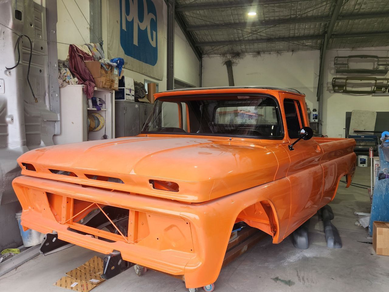 An Orange Ute is in a workshop with no wheels — MJR Auto Glass In Bowral, NSW