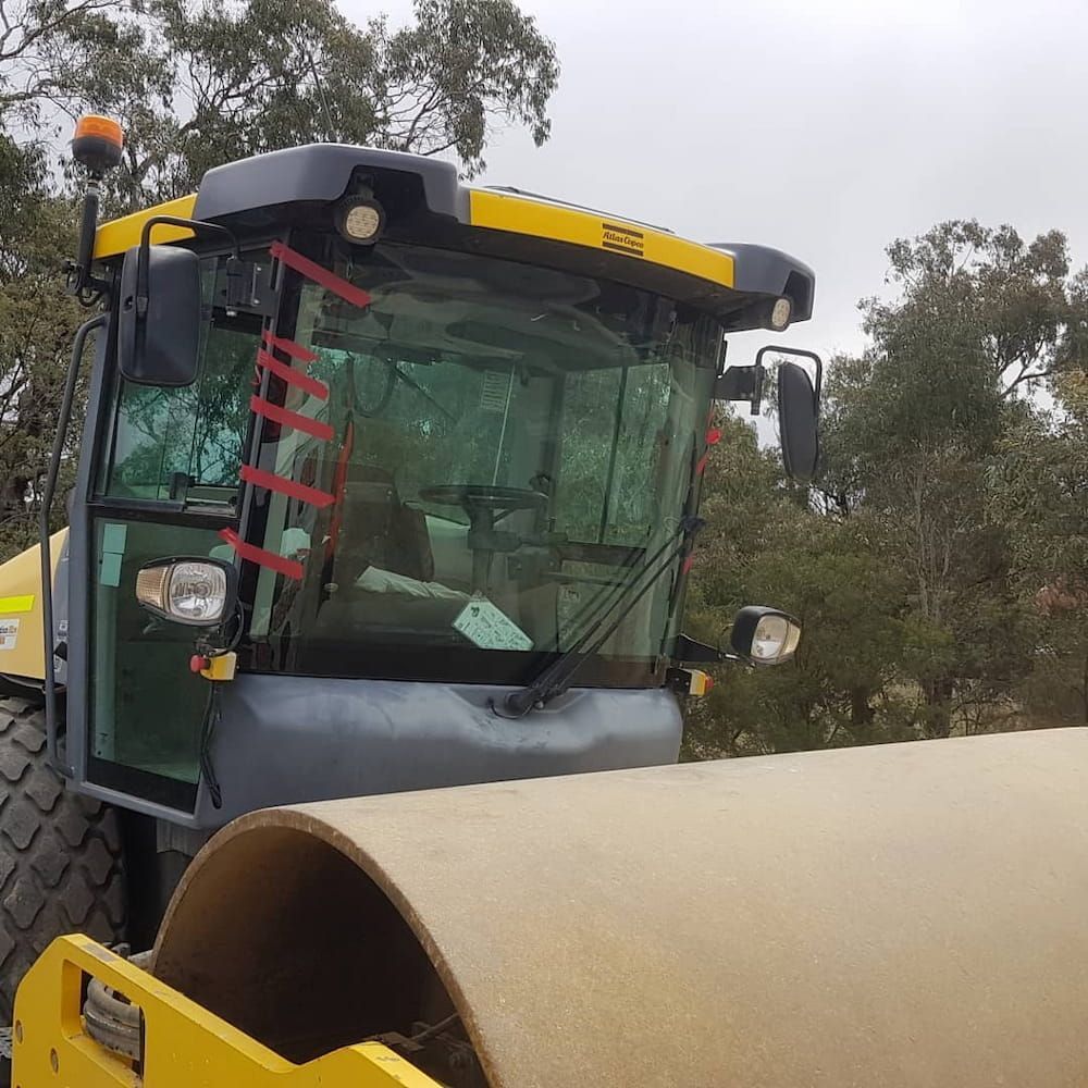 A Yellow and Black Tractor With a Large Cylinder in Front of It — MJR Auto Glass In Moss Vale, NSW