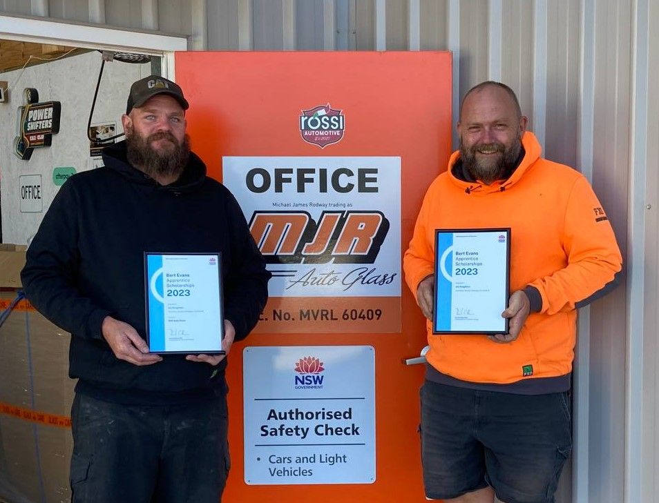 Two Men Are Standing Next To Each Other Holding Certificates In Front Of A Building — MJR Auto Glass In Goulburn, NSW