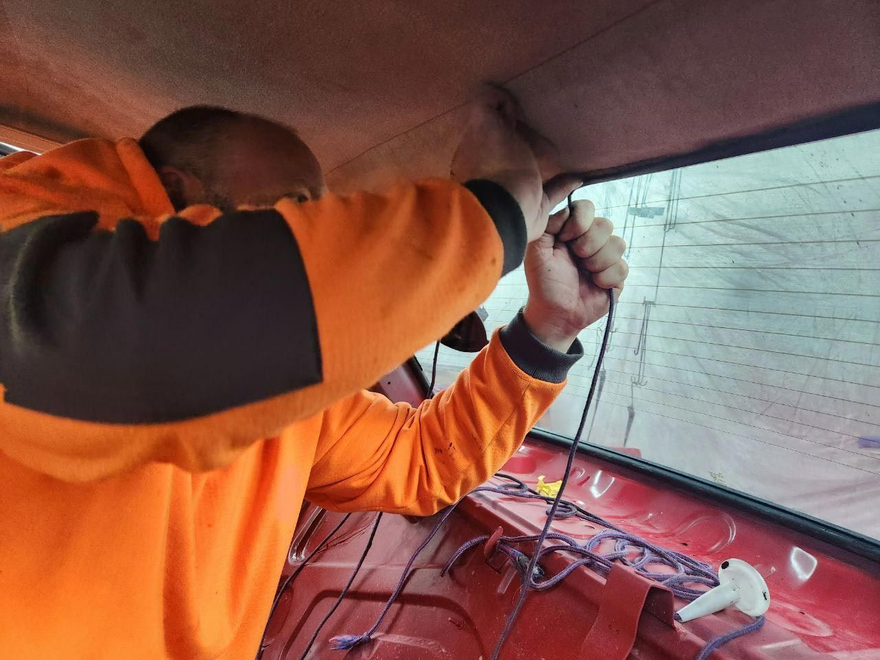 A Man In An Orange Shirt Is Working On A Car — MJR Auto Glass In Goulburn, NSW