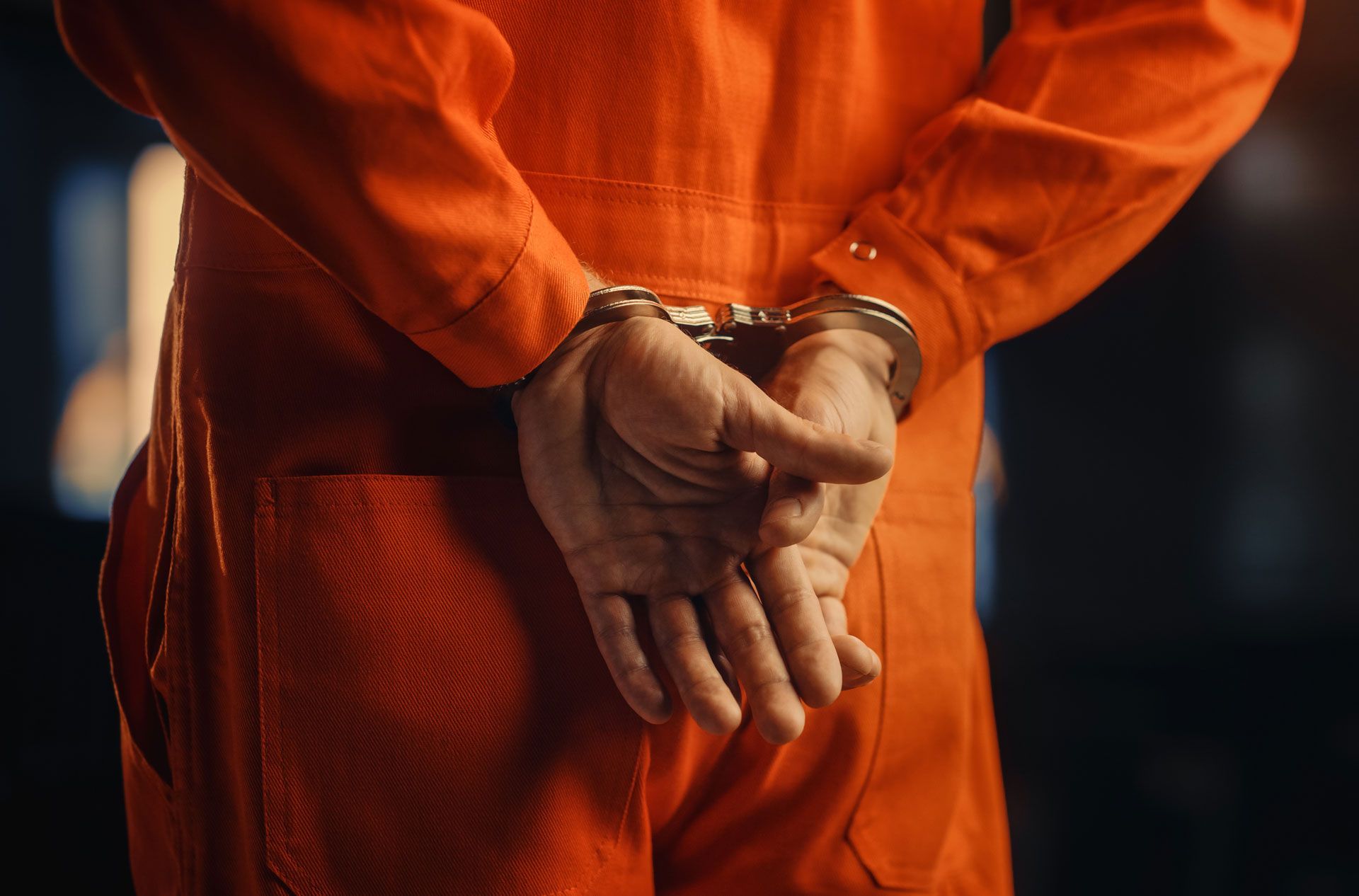 Hands cuffed behind back in an orange prison jumpsuit