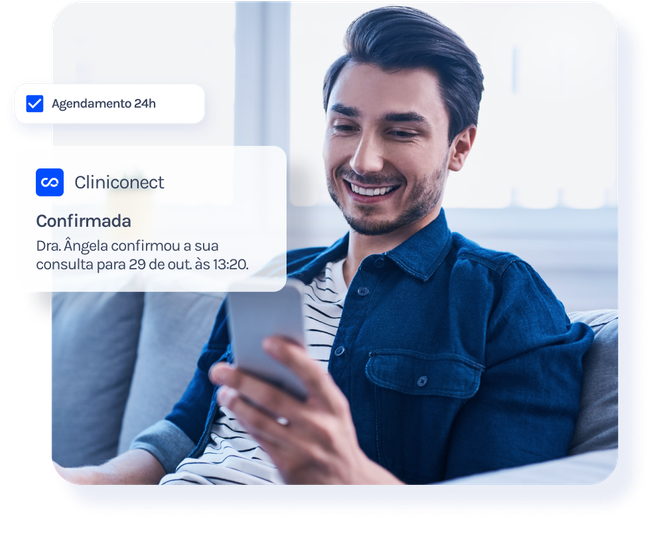 Um homem está sentado no sofá olhando para o celular.
