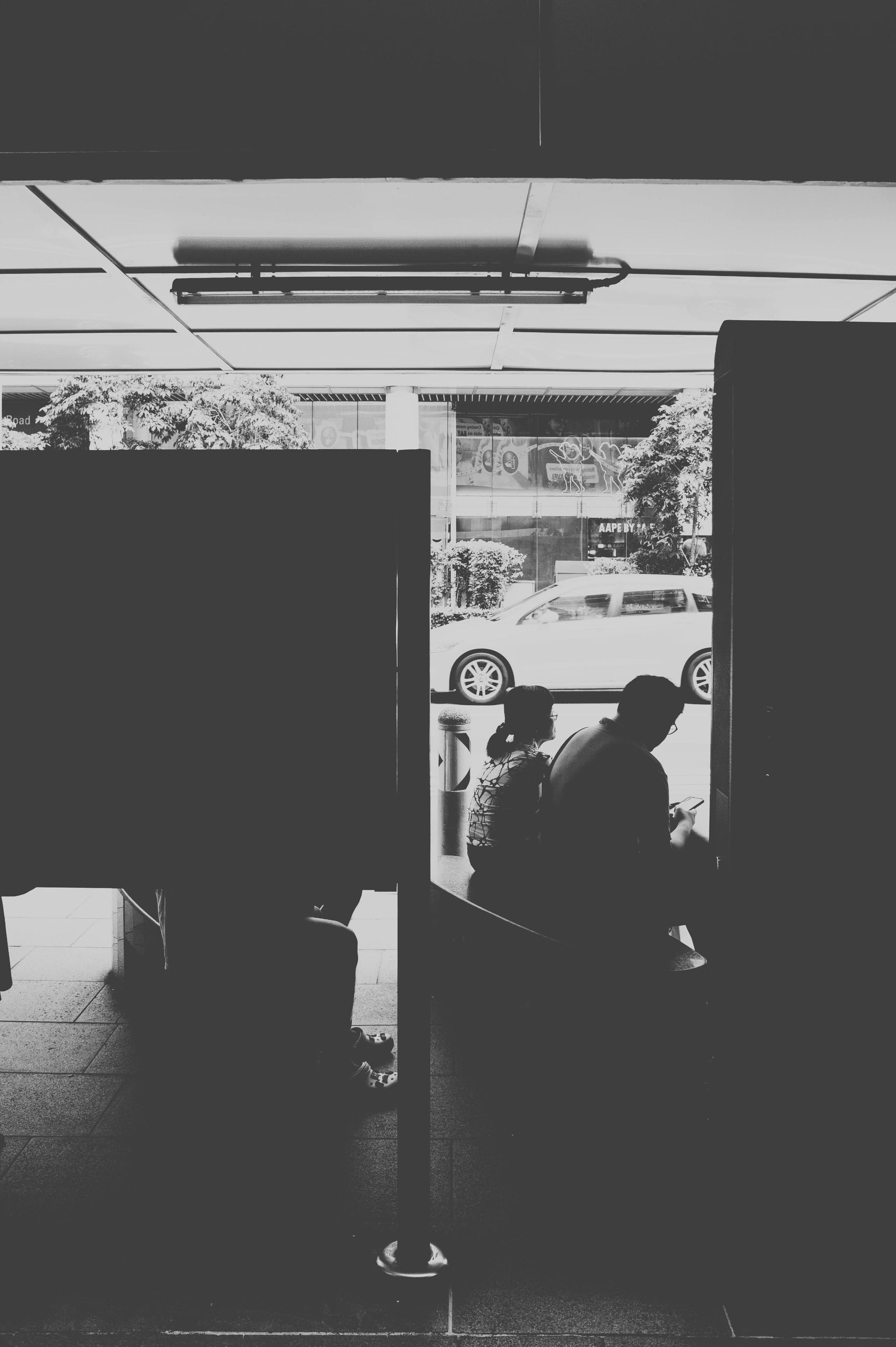 People silhouetted near a bright doorway with outdoor trees visible beyond.