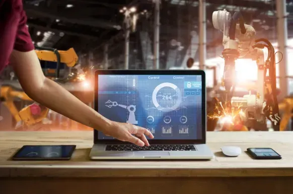 A person is using a laptop computer in a factory.