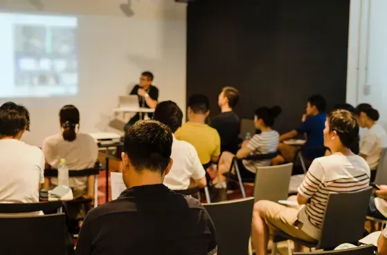 A group of people are sitting in a classroom watching a presentation.