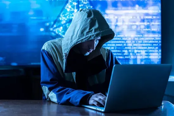 A man in a hoodie is using a laptop computer.