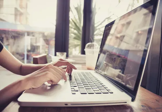 A woman is typing on a laptop computer at a table.