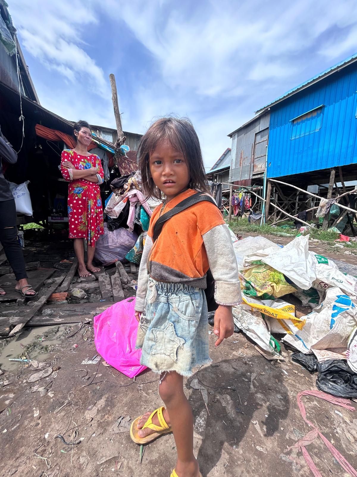A little girl is standing in front of a blue building.