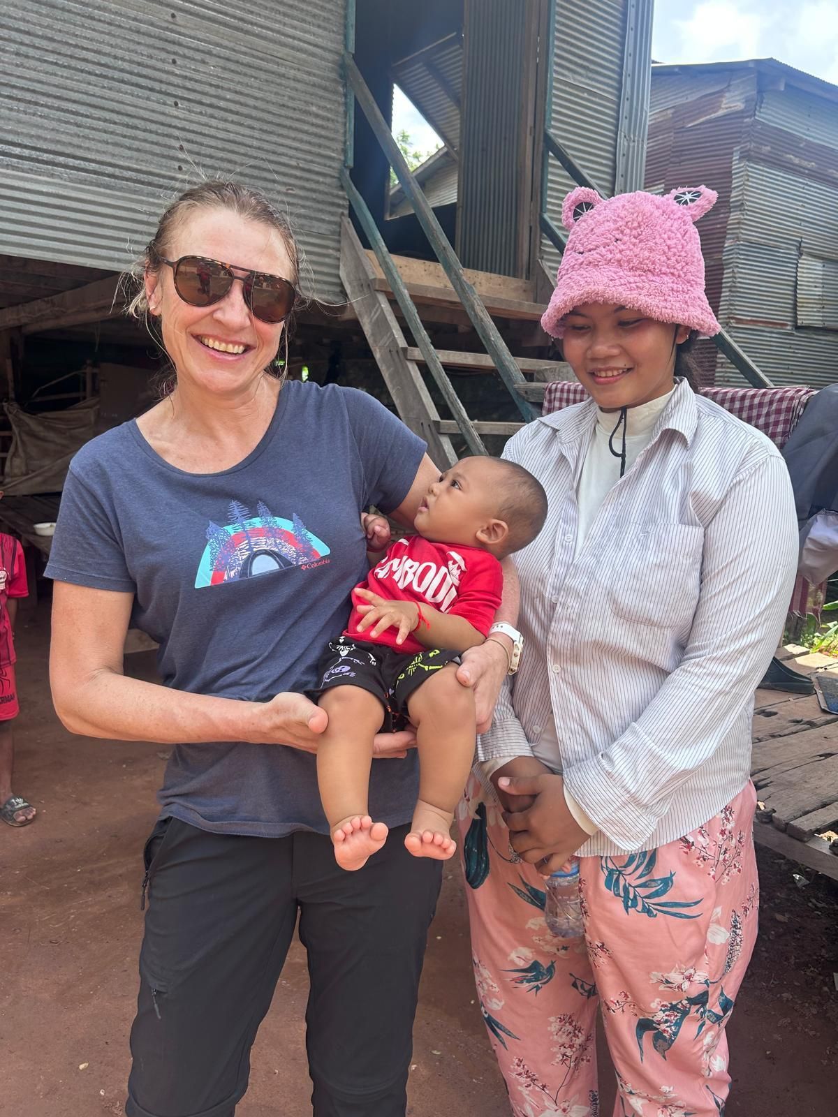 A woman is holding a baby while standing next to another woman.