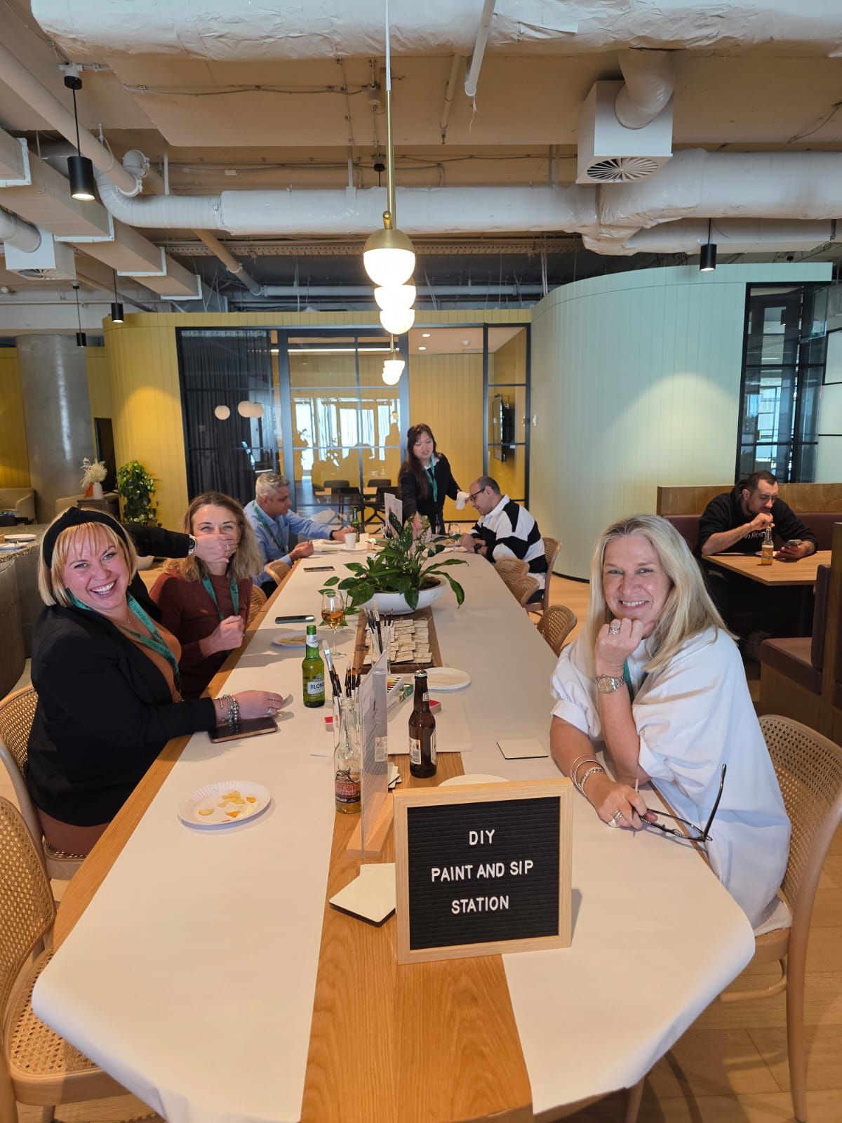 People seated at a long white table in a bright restaurant, smiling during a gathering