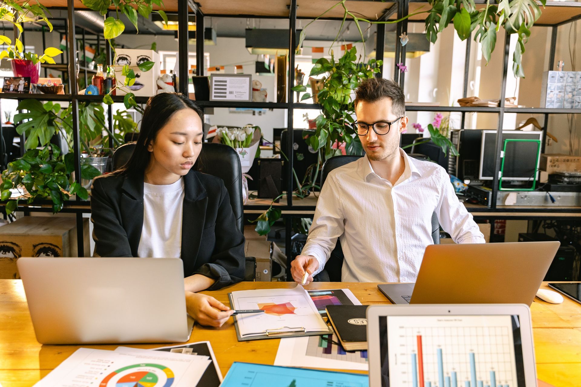 Team reviewing documents around a conference table in a bright office with laptops and papers