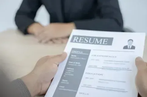 A person is holding a resume in front of a woman.