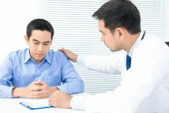 A doctor is comforting a patient who is sitting at a table.
