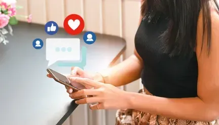 A woman is holding a cell phone in her hand.