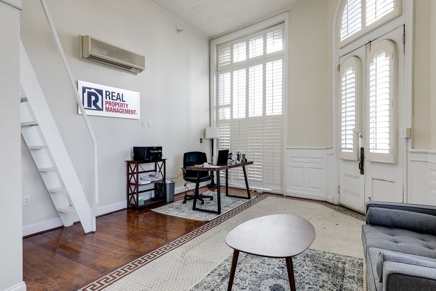 Office space with desk, rug, sofa, stairs, window, AC unit, and TV.