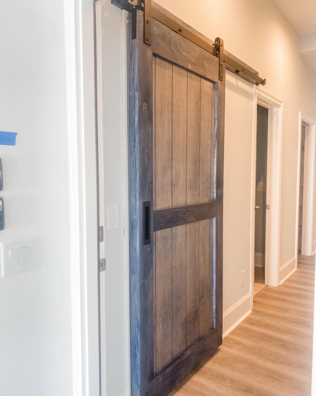 Barn door, dark stained wood, black hardware, sliding on a track in a hallway.