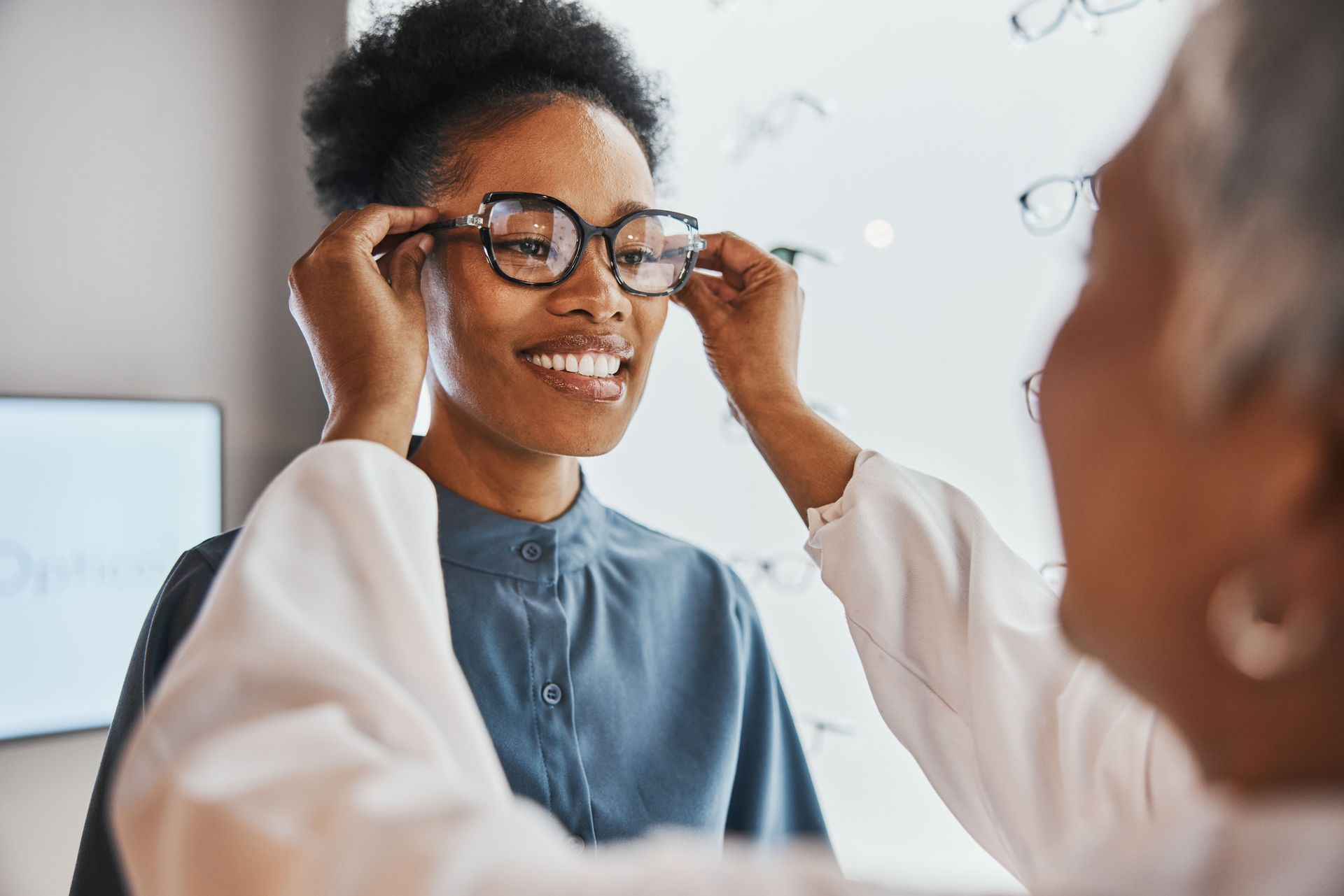 A woman is trying on glasses in front of a mirror.