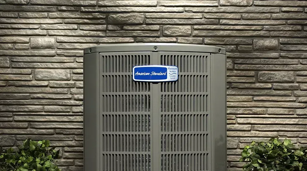 An air conditioner is sitting on the side of a brick building.