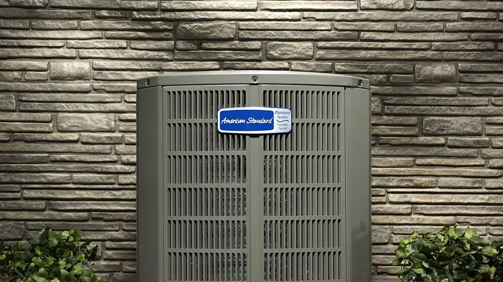 An air conditioner is sitting on the side of a brick building.