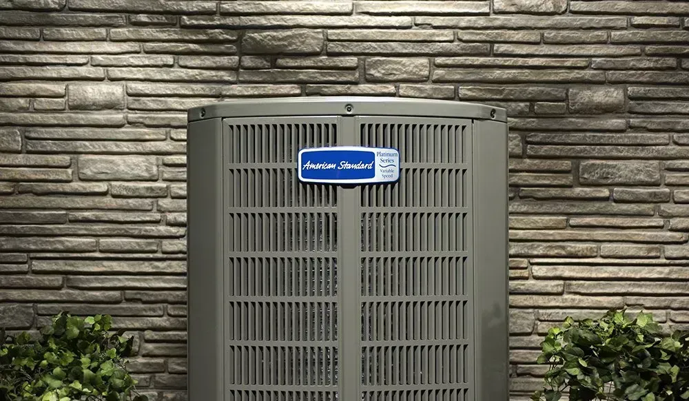 An air conditioner is sitting on the side of a brick building.