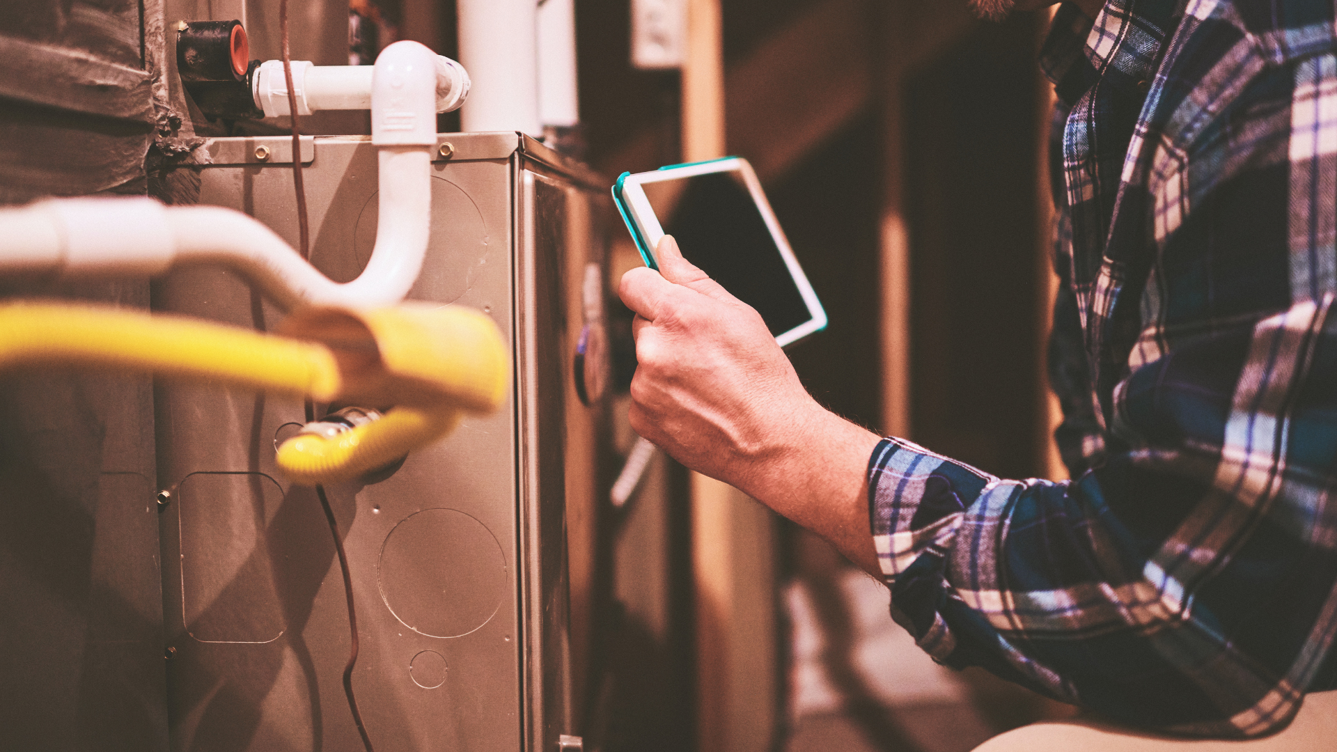A man is working on a heating system and using a tablet.